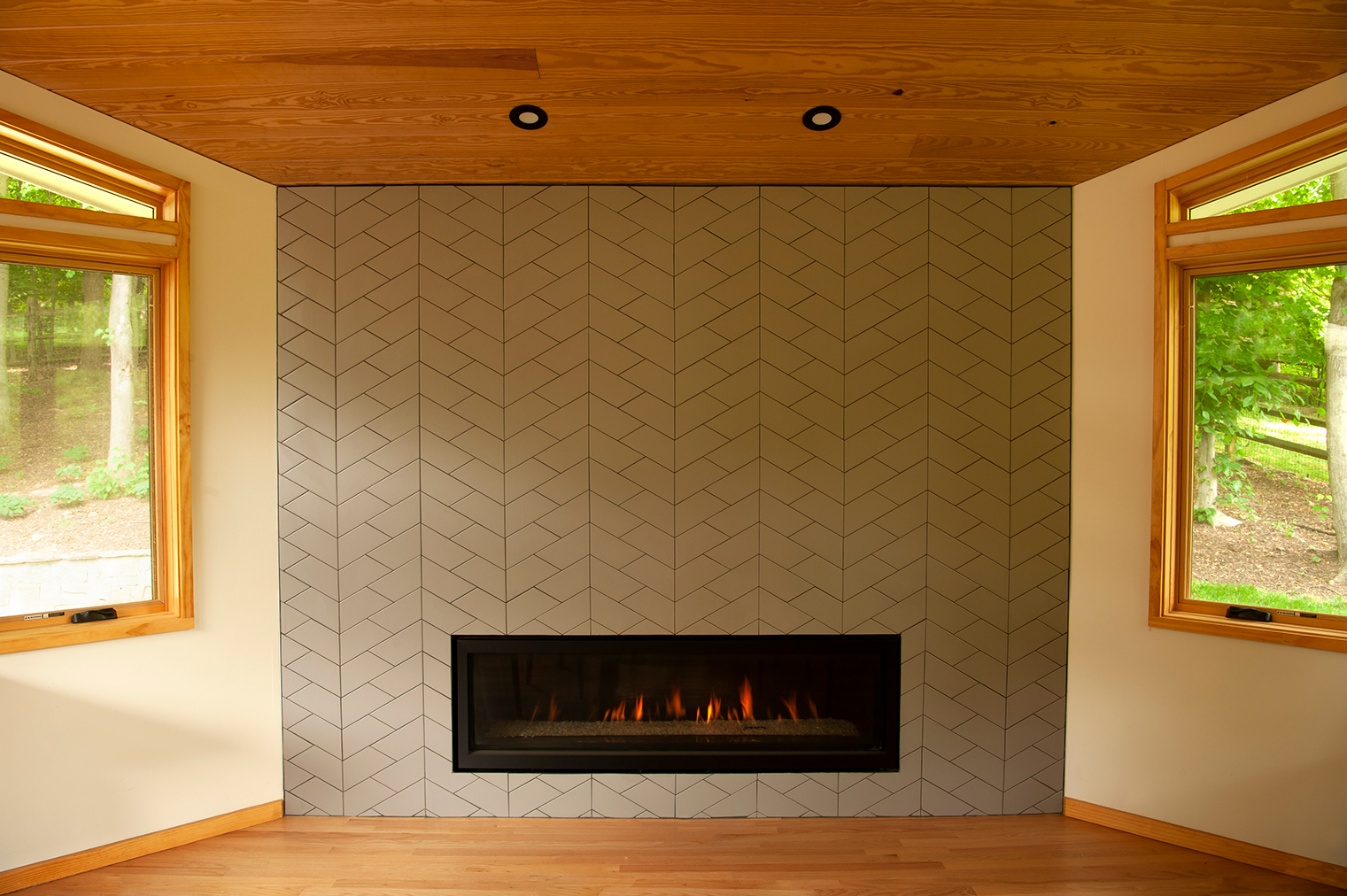 Gas fireplace set into wall of porcelain geometric tile from Ann Sacks Tile.