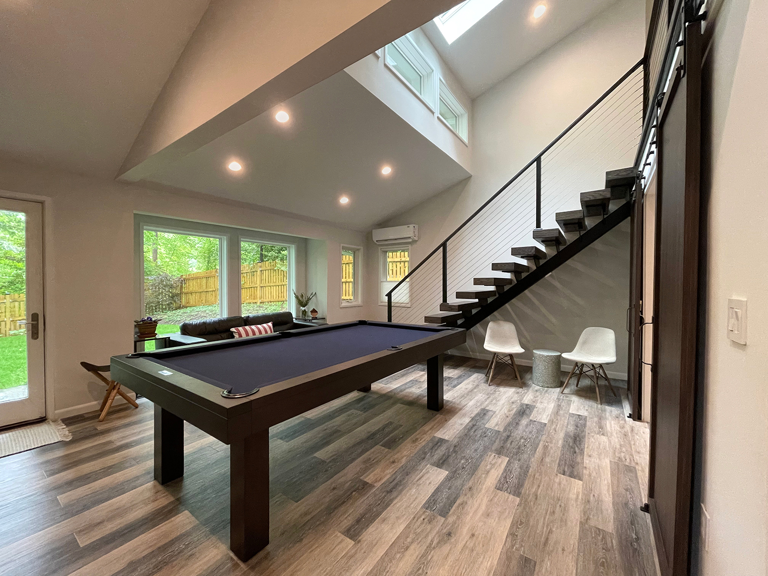 Game room with billiards table and floating stairs to loft level.